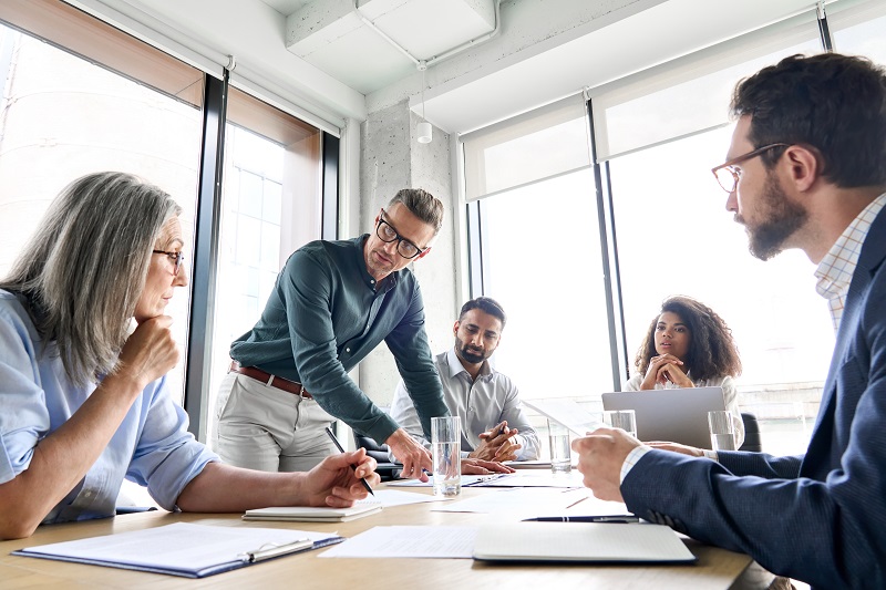 In an office space, a group of four people are having a discussion regarding their business, and the CEO leads the meeting with his ideas.